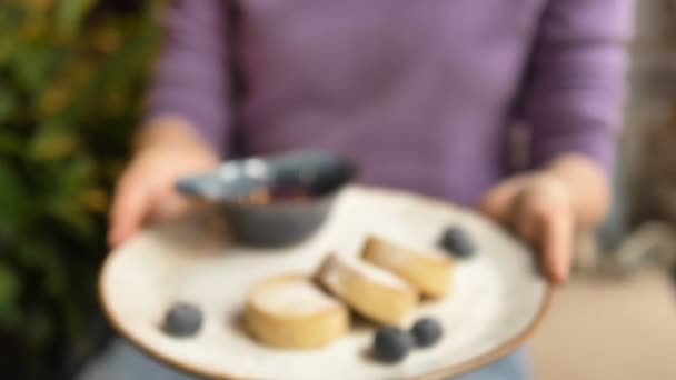 Леди протягивает руки, держа тарелку с веганским десертом — стоковое видео