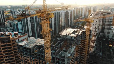 Vinçler inşaat alanında sabah güneşinde çalışır.