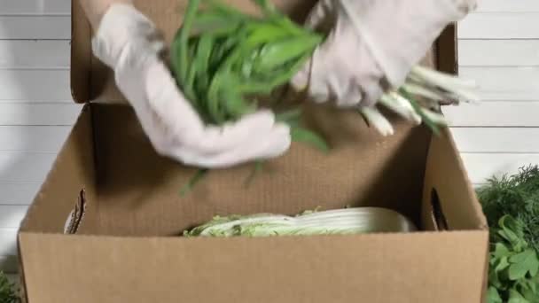 Πρόσωπο σε γάντια γεμίζει χαρτόκουτο με πράσινα τσαμπιά — Αρχείο Βίντεο