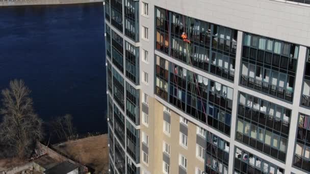 Industriklättrare i uniform hissar upp längs byggnadens fasad — Stockvideo