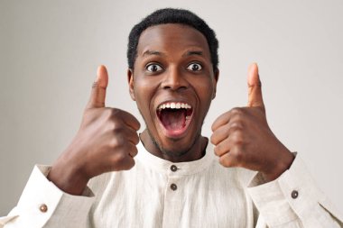 Duygusal Afrikalı-Amerikalı adam açık gri üzerinde baş parmak gösteriyor.