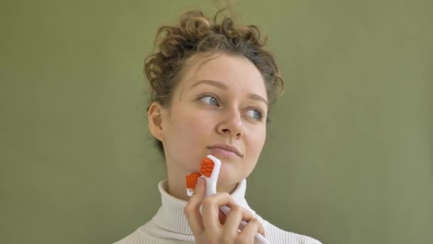 Mladá žena s kudrnaté hnědé vlasy masáže tvář po zdi — Stock video