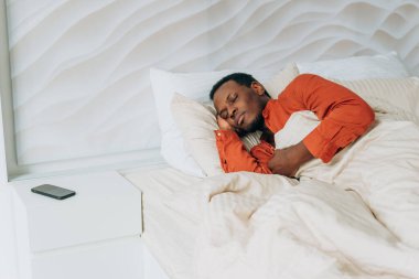 African-American man sleeps in comfortable bed at home