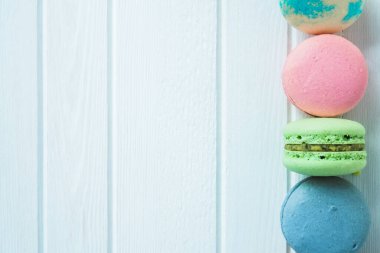 Beyaz ahşap arka planda çok renkli badem kurabiyeleri, beyaz masada badem kurabiyeleri, boşluğu kopyala.