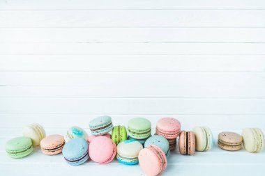 Beyaz ahşap zemin üzerinde birçok renkli badem kurabiyesi, masa üzerinde badem kurabiyesi, boşluk kopyala.