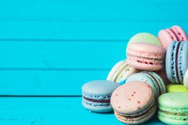 Turkuaz ahşap zemin üzerinde bir demet renkli badem kurabiyesi bir masanın üzerinde. Boşluğu kopyala