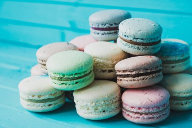 Mavi ahşap zemin üzerinde çok renkli badem kurabiyeleri, Fransız badem kurabiyeleri, yakın plan..