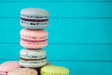 Çok renkli badem kurabiyeleri turkuaz ahşap zemin üzerinde duruyor, Fransız badem kurabiyeleri yakın plan, uzay kopyalama