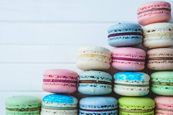 Macaroons piramis fehér fából készült háttérrel, színes mandulás sütikkel. Fénymásolási hely. — Stock Fotó