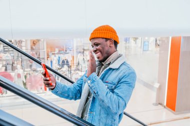 Mutlu Afro-Amerikalı adam telefonda görüntülü konuşma yapıyor.