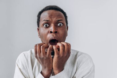 Beyaz tişörtlü, açık gri giysili, korkmuş Afro-Amerikalı adam.