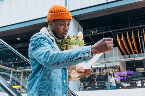 Doubting African-American man looks at receipt total in mall