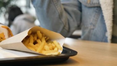 Mavi kot ceketli siyah adam sarı patates kızartması alır.