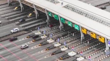 Otoparkın yanındaki asfalt yolda arabalar geçitin altından geçiyor.