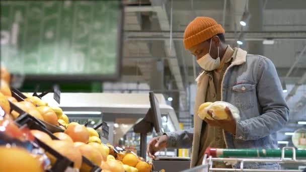 Профессиональный покупатель в маске выбирает желтые лимоны — стоковое видео