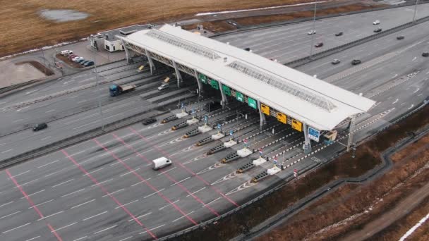 Voertuigen rijden onder poort op asfaltweg tussen velden — Stockvideo