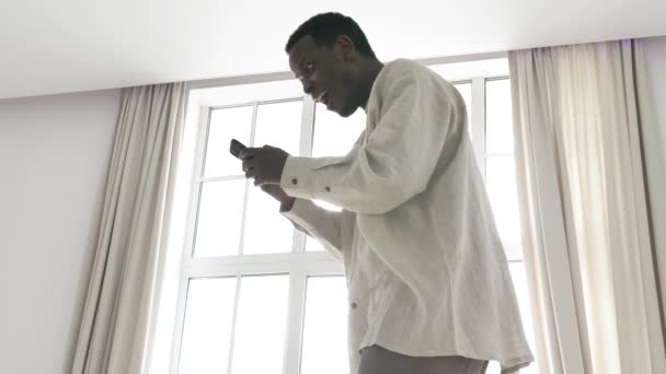 Zabawny Afroamerykanin zostaje zaskoczony patrząc w telefonie — Wideo stockowe