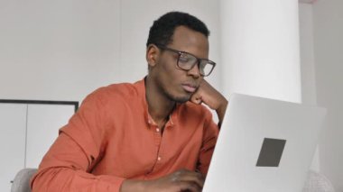 Afro-Amerikalı adam masada dizüstü bilgisayarın yanında uyuyakalıyor.