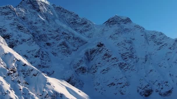 Açık mavi gökyüzünün altında karla kaplı resimli bir dağ zirvesi. — Stok video