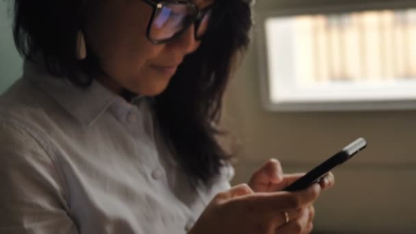 Señora en blusa blanca y tipos de gafas en el teléfono celular negro — Vídeo de stock