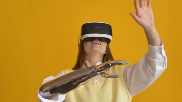Doamnă uimită cu braț bionic folosește căști VR pe galben — Videoclip de stoc