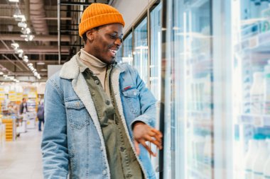 Yeşil sepetli Afro-Amerikalı adam dükkan boyunca yürür.