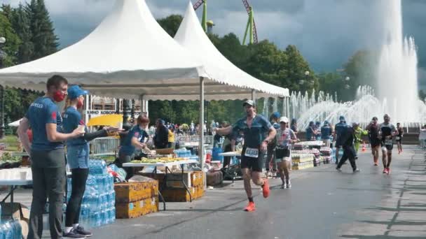 En manlig maraton löpare passerar en tom plast vattenflaska till en volontär under en Ironman ras i slow motion — Stockvideo