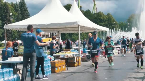 A sportolók férfiak és nők vasember triatlont futnak, a sportolók vizet isznak az étkezési pontnál lassított felvételen. — Stock videók