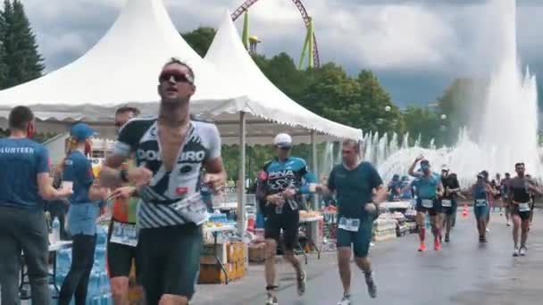 Athlètes hommes et femmes courent triathlon fer à repasser, athlètes boivent de l'eau au point de restauration au ralenti — Video