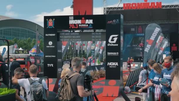Hardy athletes finish the Ironman triathlon on the red carpet to the applause of the audience and fans in slow motion — Stock Video