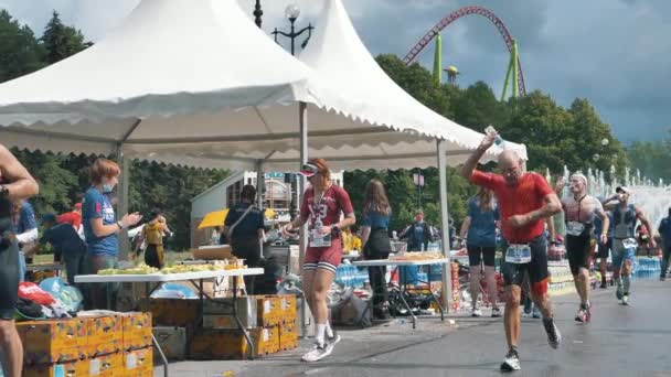 A hardy group of athletes runs a grueling ironman race and drinks water and eats at a distance, athletes run a marathon — Stock Video