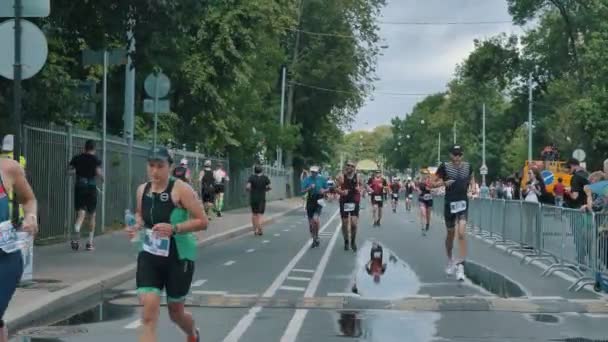 Triatletler, güneşli bir günde demir bir adamın üzerinde maraton koşar ve enerji jelleri ve izotonik enerjiler yerler. — Stok video
