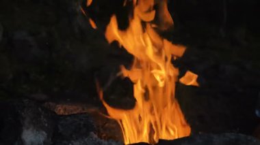 Parlak alevler gecenin karanlığında taşların yanında yanıyor.