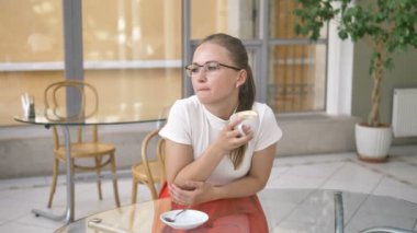 Bardaklı kadın kafede oturmuş kahve içiyor.