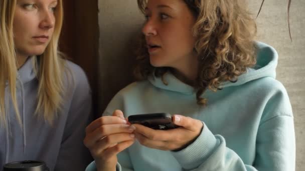 Positieve vrouwen gebruiken mobiele telefoon om te surfen op internet in cafe — Stockvideo