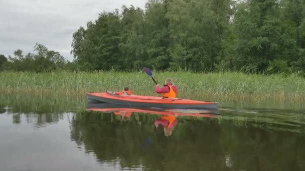 Feliz madre filas de kayak con niño navegando a lo largo de gran lago — Vídeos de Stock