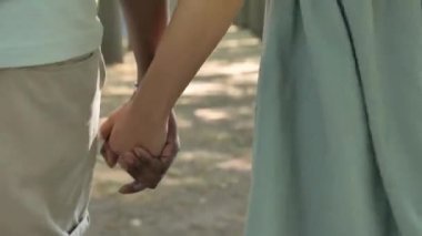 Farklı ırktan çiftler şehir parkında el ele yürür.