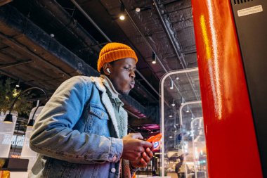 Afro-Amerikalı bir adam abur cubur sipariş etmek için self servis büfesi kullanıyor.