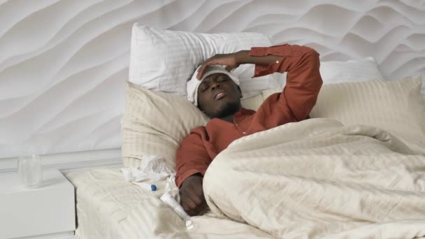 Homem afro-americano com remendo na cabeça pílulas e termômetro — Vídeo de Stock