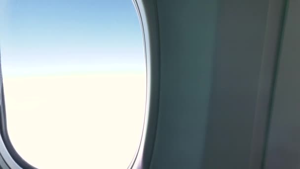 若い女性旅行者は飛行機の窓から外を眺め、飛行中に医療マスクを着用します。 — ストック動画
