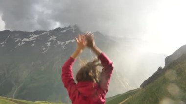 Mutlu kadın gezgin, gün batımında elleri havada, yağmurun altında sevinçten zıplar.