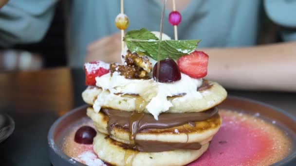 Mujer vierte miel en la pila de panqueques con chocolate — Vídeos de Stock