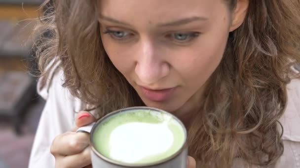 Mulher com cabelos claros bebe capuccino de copo de porcelana — Vídeo de Stock