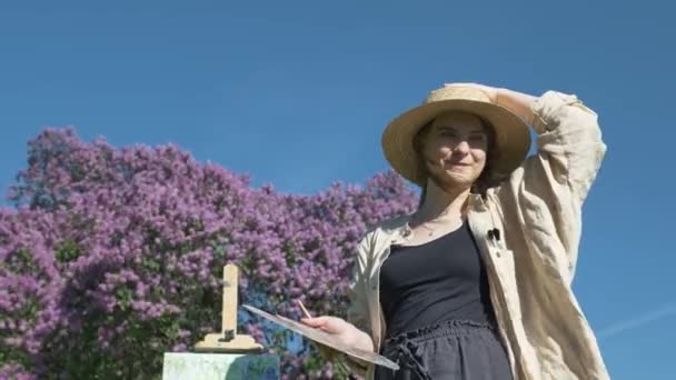 Joven pintora en sombrero de paja y pintura de camisa lila — Vídeos de Stock