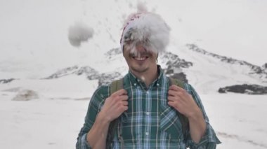 Dağların arkasında, Noel şapkalı komik bir adamın yüzüne bir kartopu düşer.