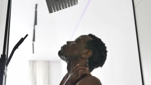 アフリカ系アメリカ人男性は、光バスルームで熱いシャワーを取ります — ストック動画