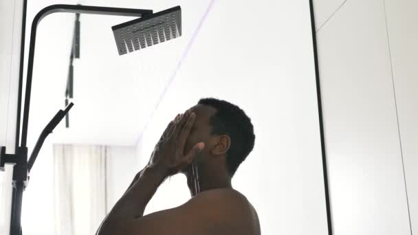 Afroamerikansk man tar varm dusch i ljust badrum — Stockvideo