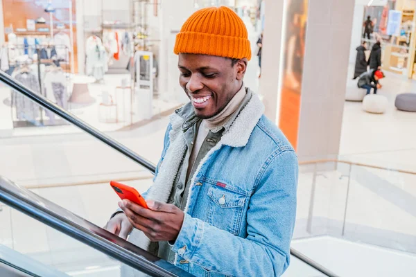 Щасливий афро-американець використовує відеобесіду по телефону в торговому центрі — стокове фото