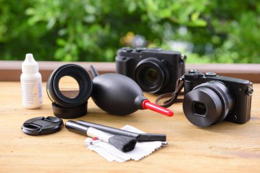 Kamera ve lens bakımı. Kamera temizleme seti ve kamera vitesleri ahşap masada..