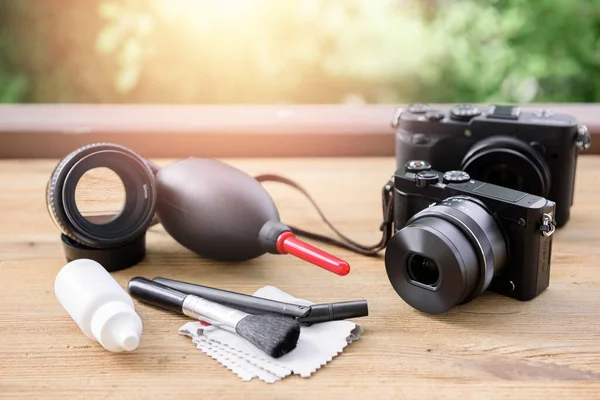 Camera and lens care. Camera cleaning kits and camera gears on wooden desk.